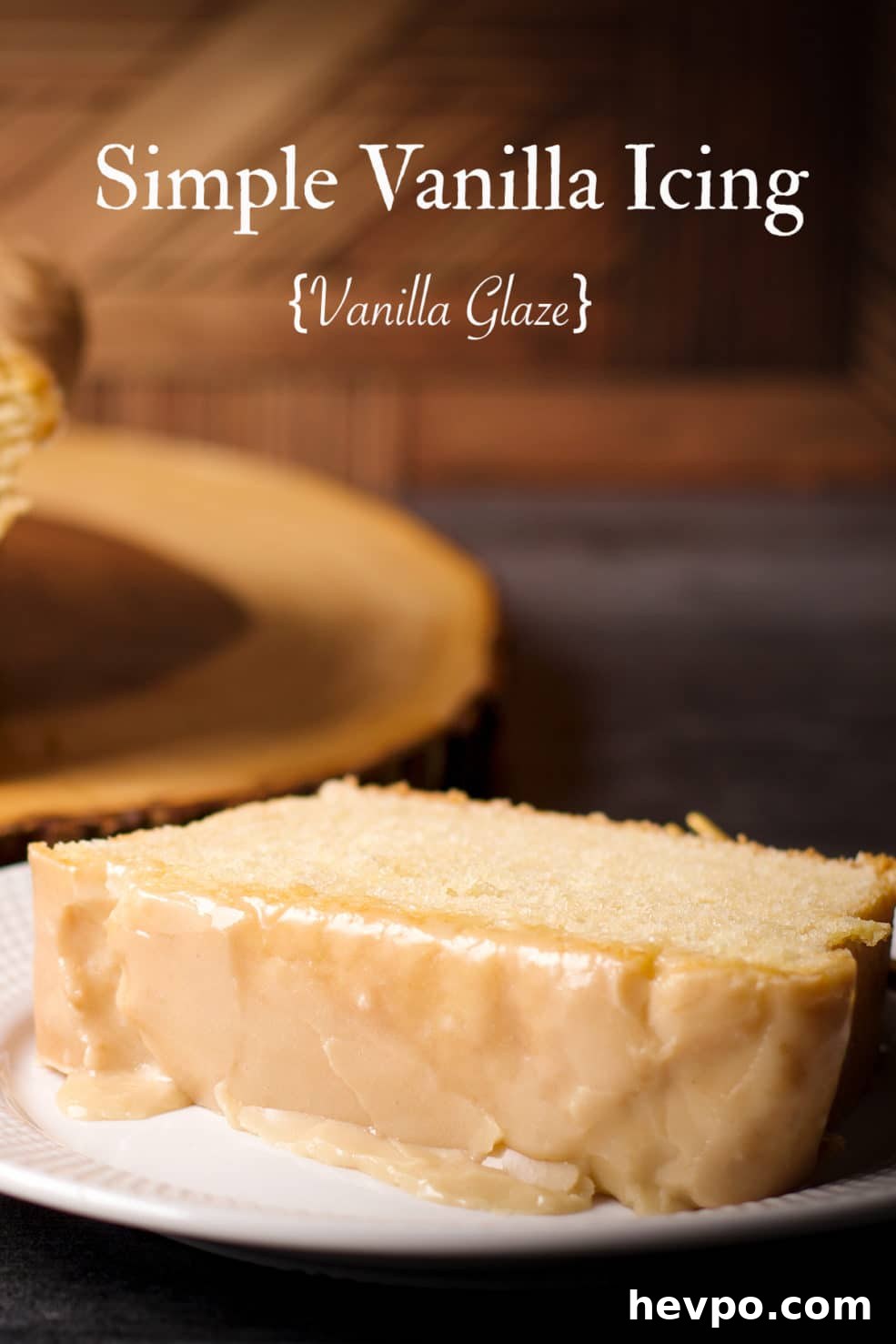 A slice of loaf cake with vanilla icing on a white plate.