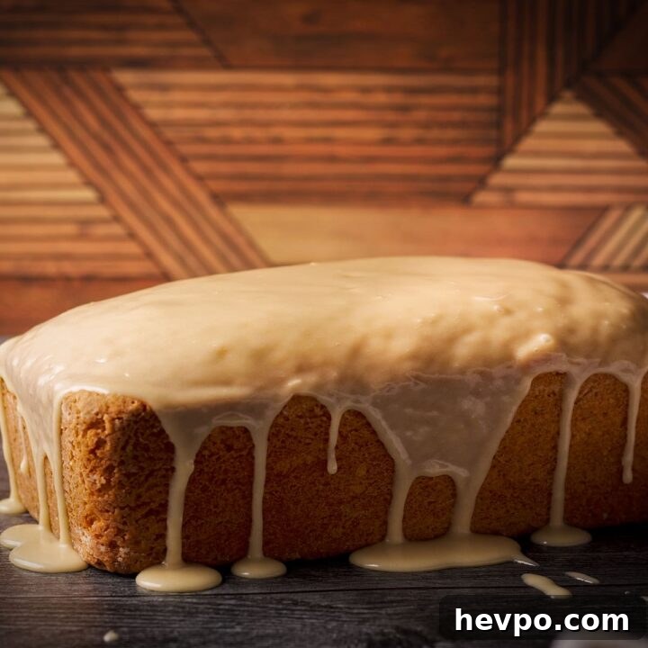 A loaf cake covered in vanilla icing, the icing dripping down the sides of the cake.
