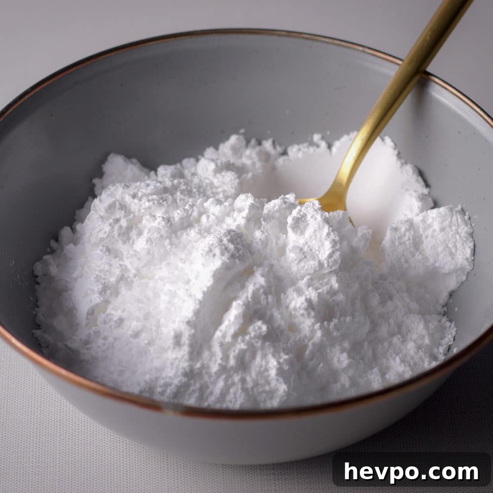 Powdered sugar and a gold spoon in a blue bowl.