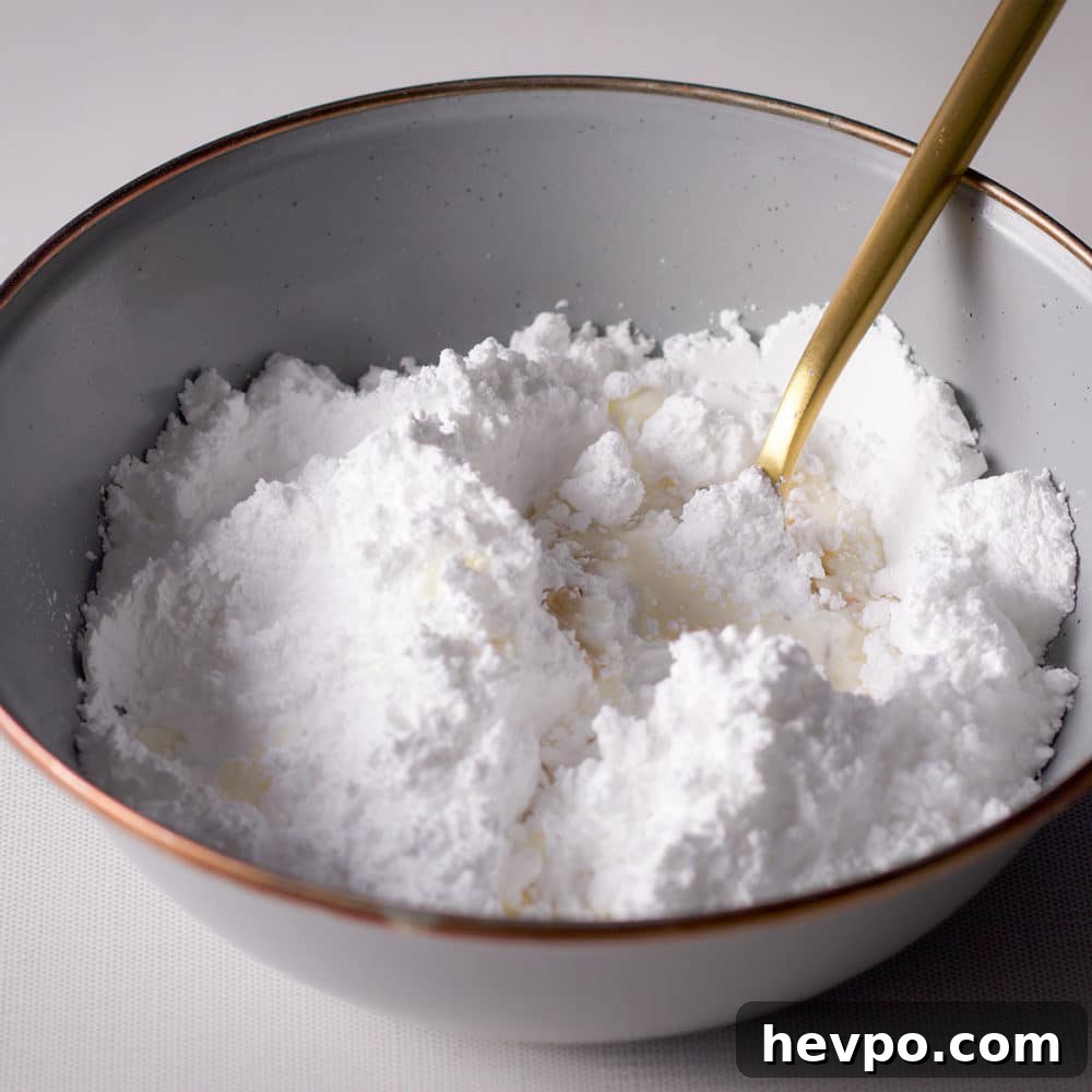 Powdered sugar, heavy cream, and a gold spoon in a blue bowl.