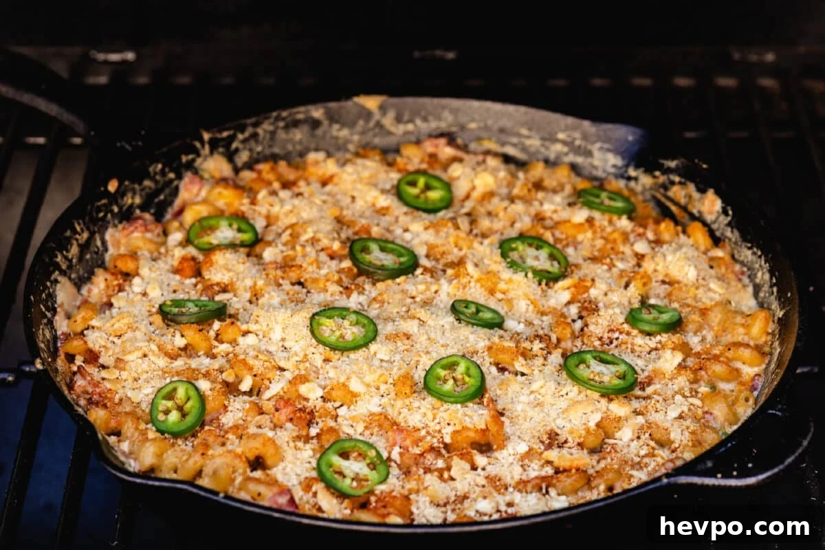Smoky jalapeno popper mac and cheese A cast iron skillet filled with a pasta and jalapeño dish on the grates of a smoker.