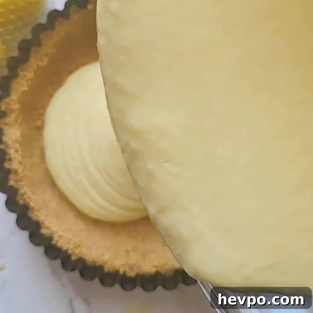 Pouring lemon icebox pie filling into graham cracker crust.