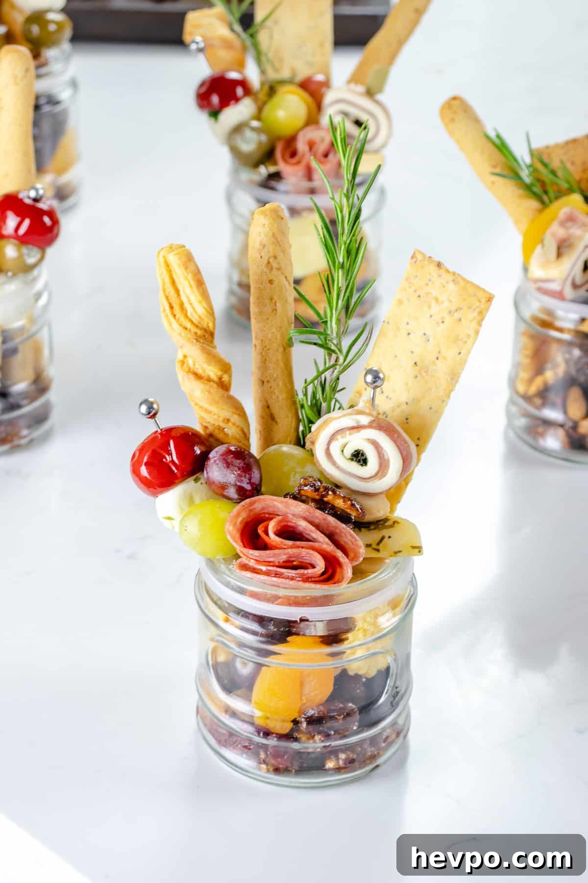 Jarcuterie cups on table with cheeses and meats.
