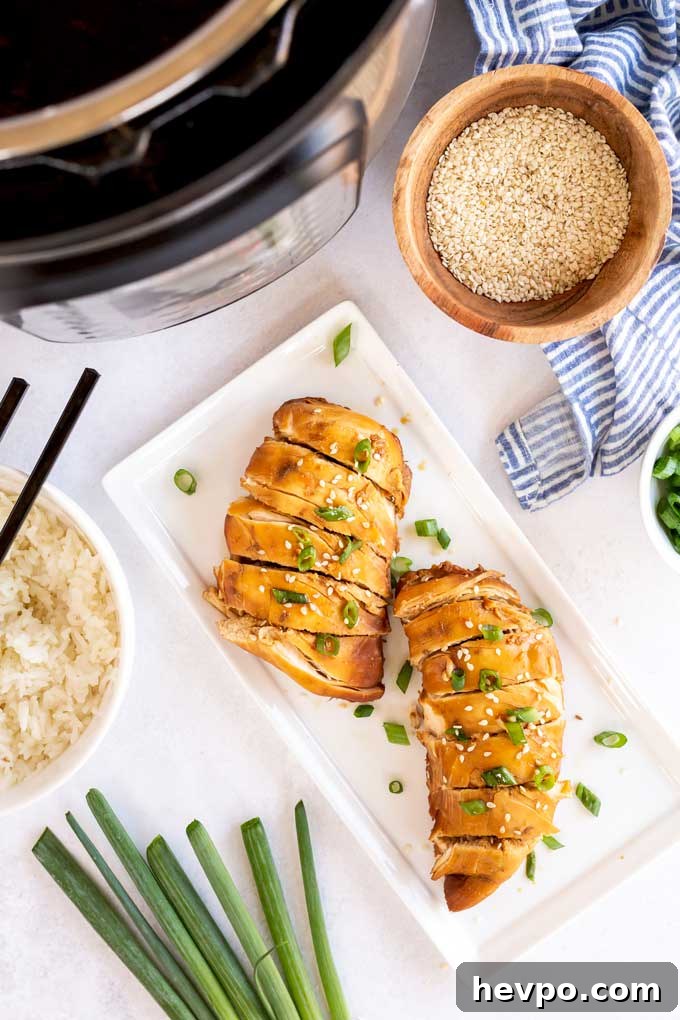 Shredded Teriyaki Chicken Made in the Instant Pot 7 Sliced boneless chicken breast in teriyaki sauce on a white plate.