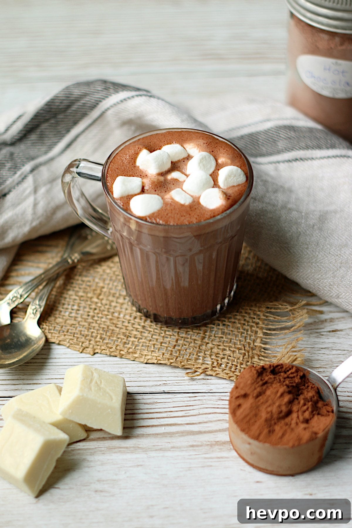 Homemade hot chocolate with mini marshmallows in a clear glass mug.
