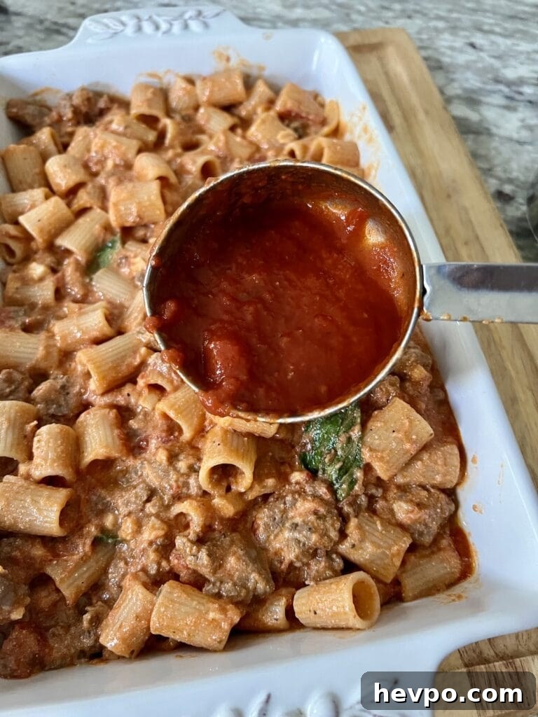 Baked Rigatoni al Forno with Sausage and Beef: Rustic Oven Pasta 13 Adding tomato sauce to the baking dish.