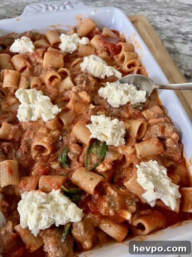 Baked Rigatoni al Forno with Sausage and Beef: Rustic Oven Pasta 14 Adding cheese mixture to the top of the baked rigatoni and sausage mixture in baking dish.