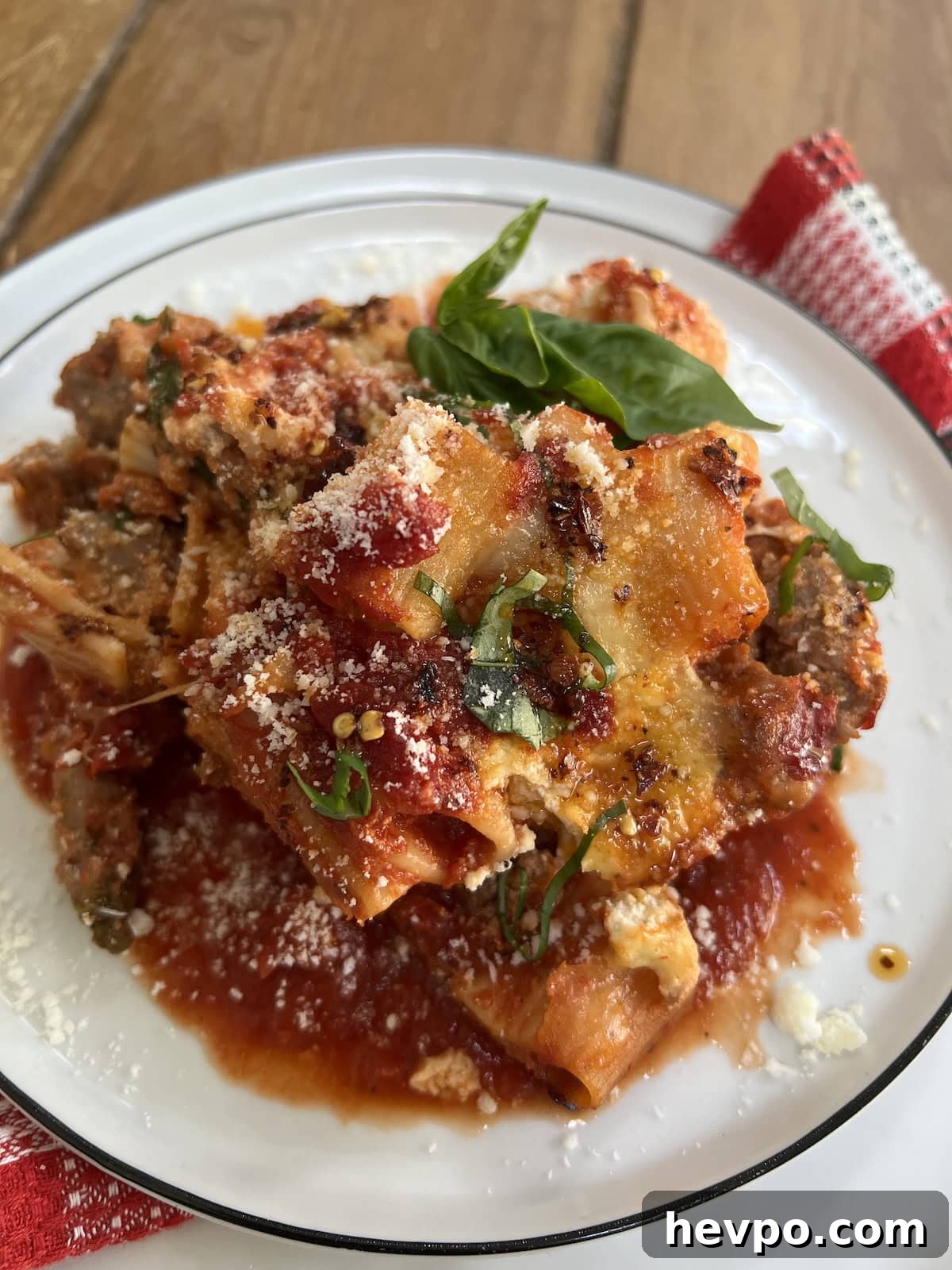 Baked Rigatoni al Forno with Sausage and Beef: Rustic Oven Pasta 20 Close-up of a portion of pasta al forno in white dish with basil garnish.
