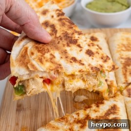 Sizzling Steak and Pepper Fajita Quesadilla Recipe 7 Hand holding cheesy chicken fajita quesadilla slice with melted cheese stretch