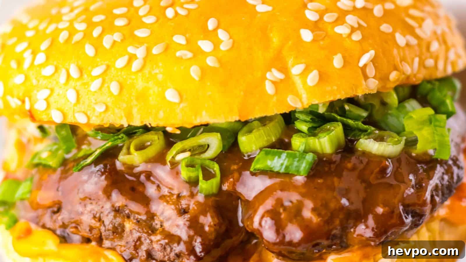 31 Copycat Restaurant Recipes for Delicious Nights In 12 Close-up of a hamburger with a sesame seed bun, beef patty, green onions, and rich brown sauce.
