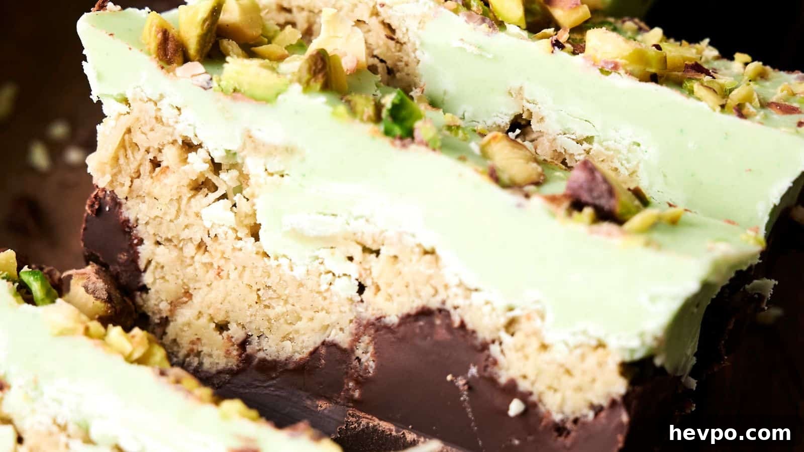 31 Copycat Restaurant Recipes for Delicious Nights In 18 Close-up of sliced dessert bars with layers of chocolate, crumbly filling, and green topping, garnished with chopped pistachios.