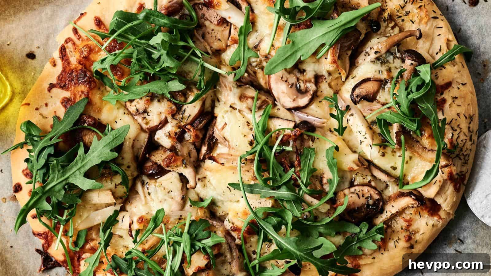 31 Copycat Restaurant Recipes for Delicious Nights In 22 Close-up of a pizza topped with arugula, mushrooms, cheese, and herbs on a parchment paper.