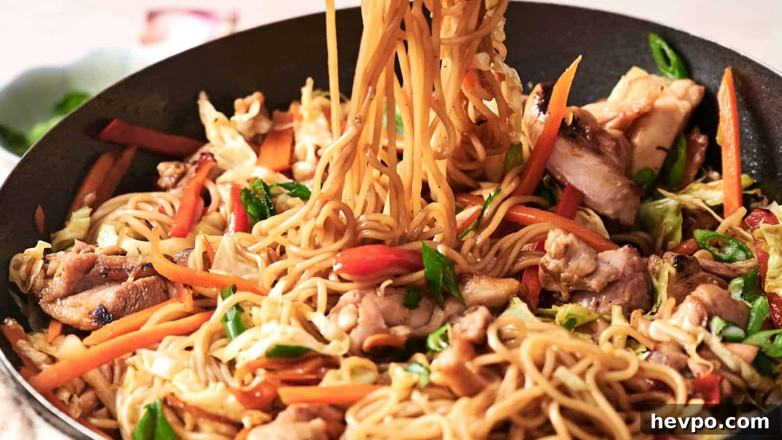 31 Copycat Restaurant Recipes for Delicious Nights In 23 Stir-fried noodles with vegetables and chicken in a pan, featuring carrots, cabbage, and green onions.