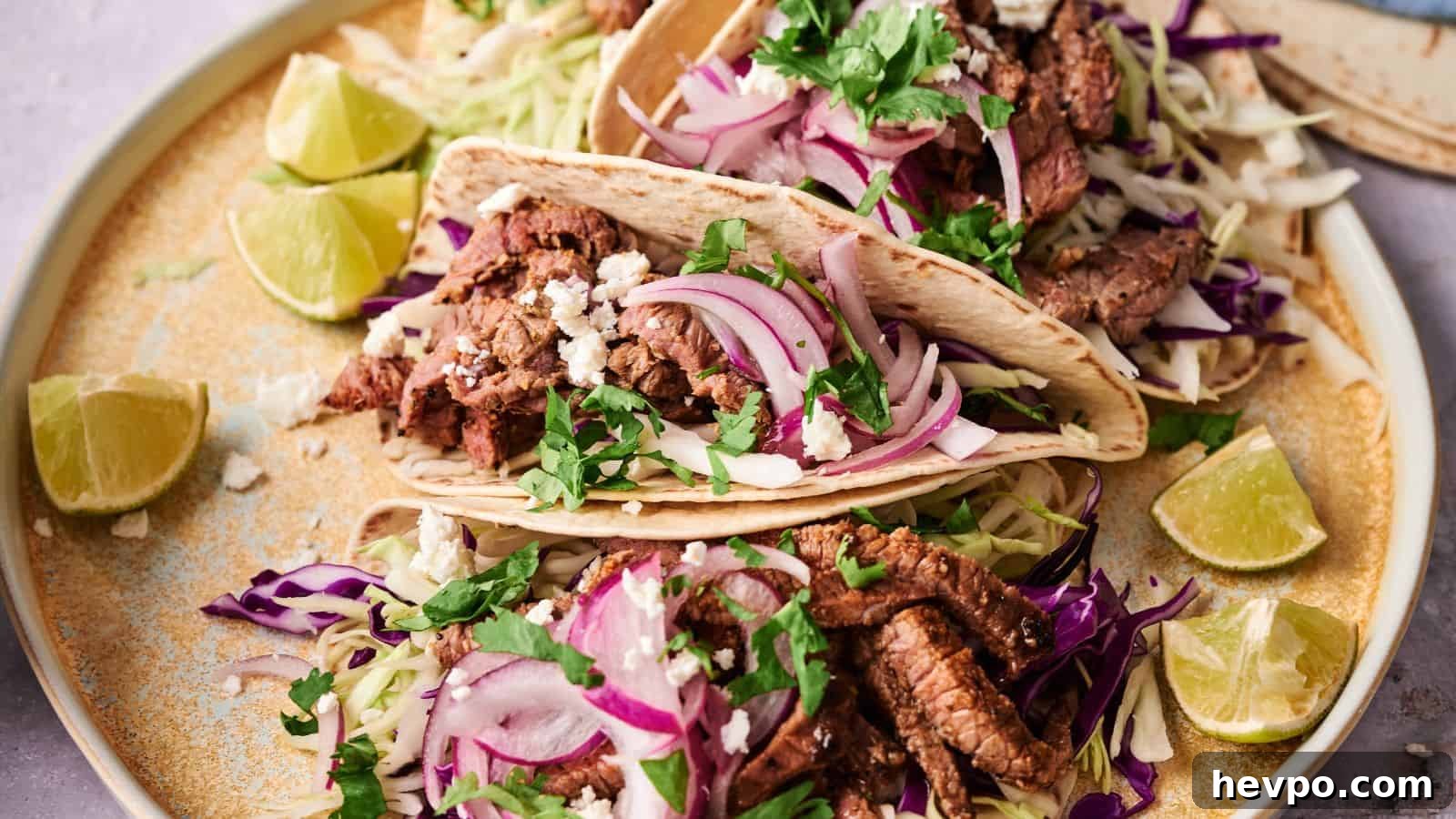 31 Copycat Restaurant Recipes for Delicious Nights In 32 Two beef tacos on a plate, topped with sliced red onions, shredded cabbage, cilantro, and crumbled cheese, surrounded by lime wedges.