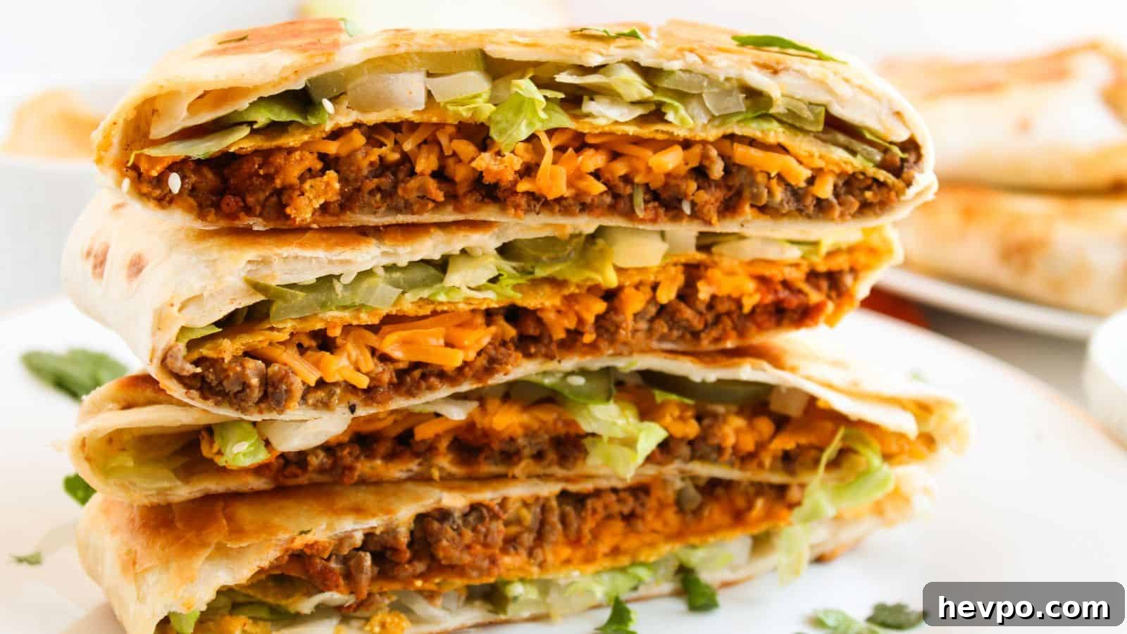 31 Copycat Restaurant Recipes for Delicious Nights In 7 Close-up of a stack of folded tortillas filled with beef, melted cheese, lettuce, and onions on a white plate.