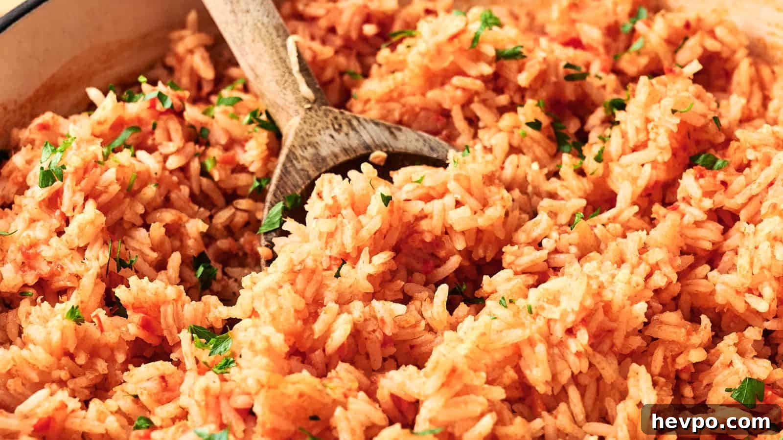 31 Copycat Restaurant Recipes for Delicious Nights In 8 A close-up of cooked Mexican rice with a wooden spoon, garnished with chopped parsley.