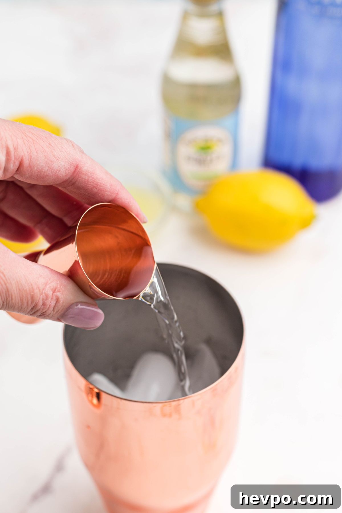 Citrus Lemon Drop Martini Recipe — Zesty Cocktail Guide 4 Vodka being poured into cocktail shaker filled with ice.