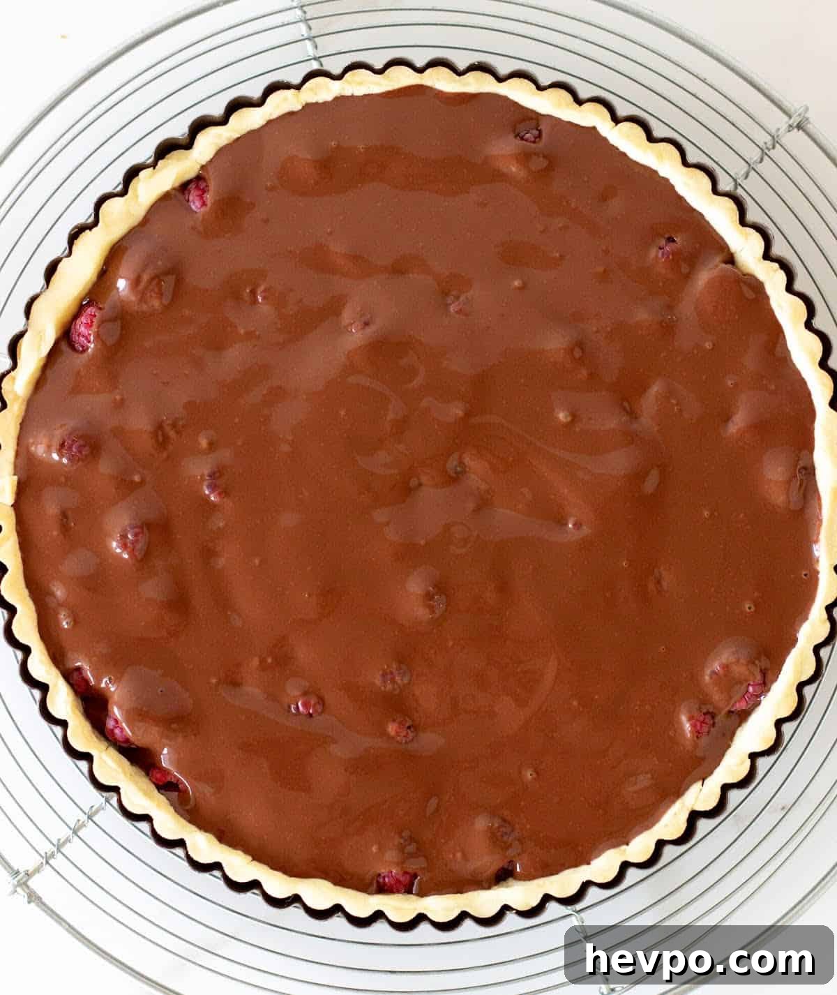 Top view of chocolate tart in the pan on a wire rack before baking. White marble surface.