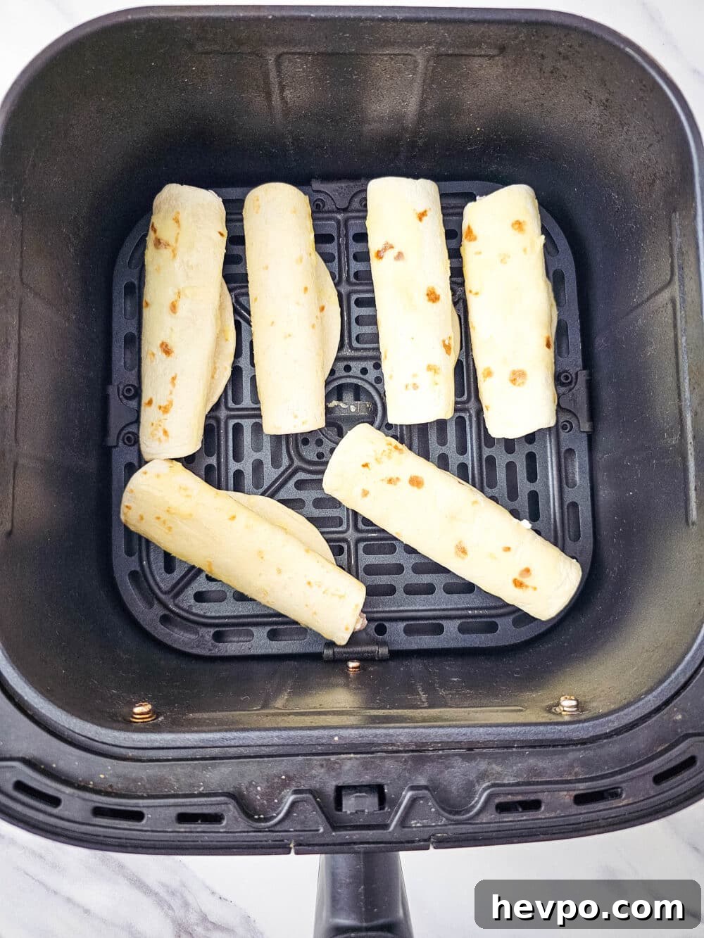 filled tortillas in an air fryer basket