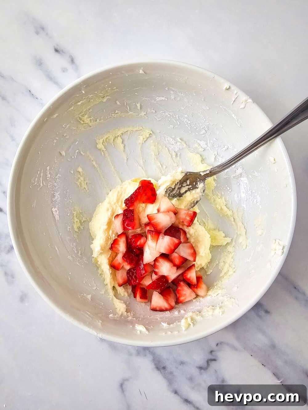 mixed cream cheese and sweetener in a bowl with strawberries added