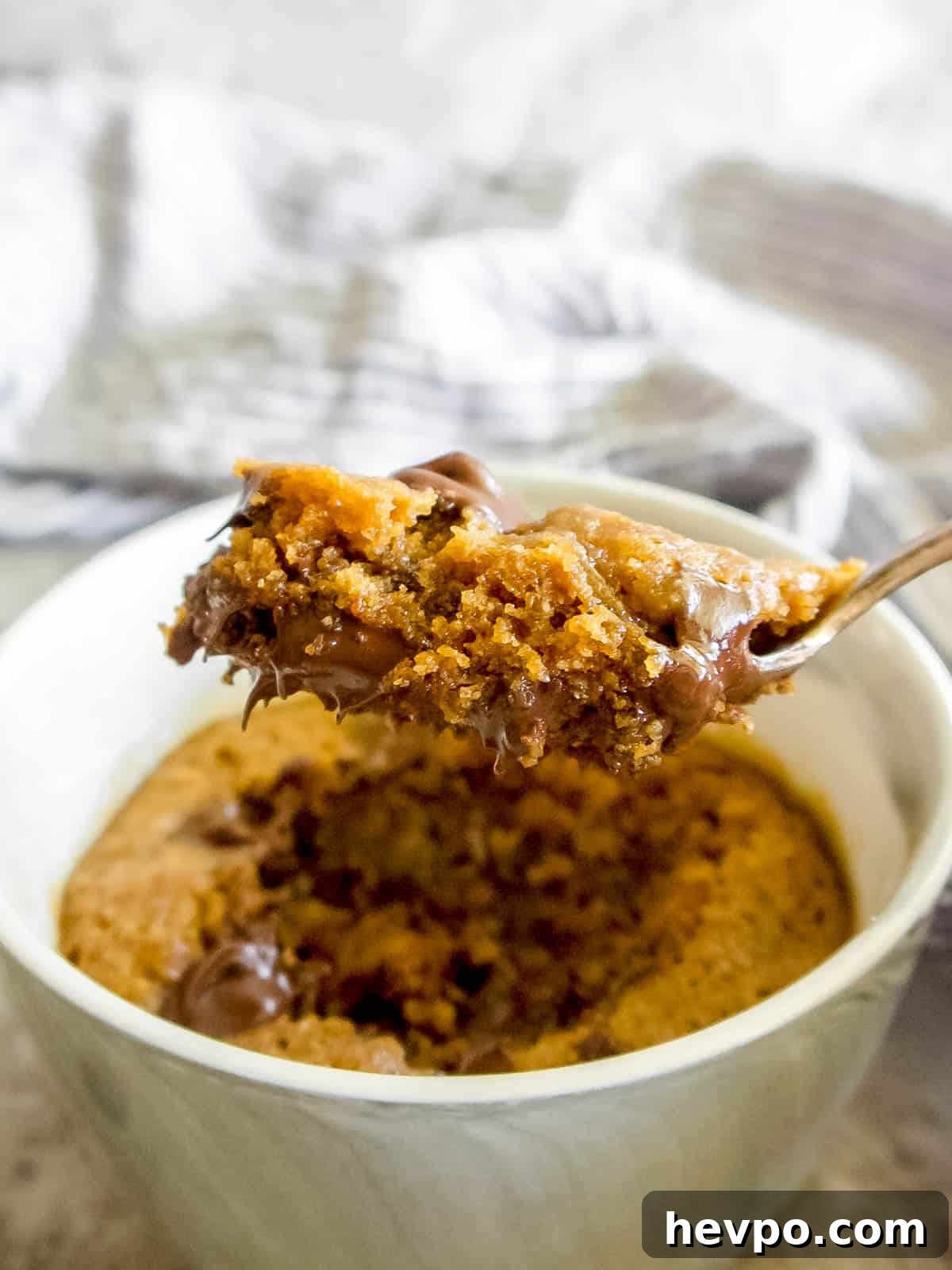A spoon of Gluten-free Mug Cookie being lifted out of a ramekin. 