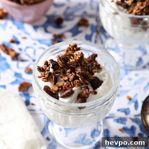 Two glass containers of yogurt topped with homemade granola on a tiled surface