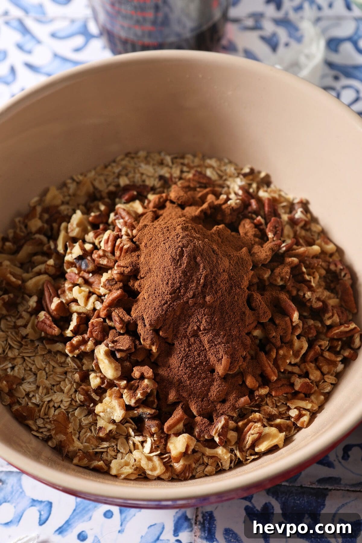 A large bowl with oats, nuts and cinnamon before tossing together