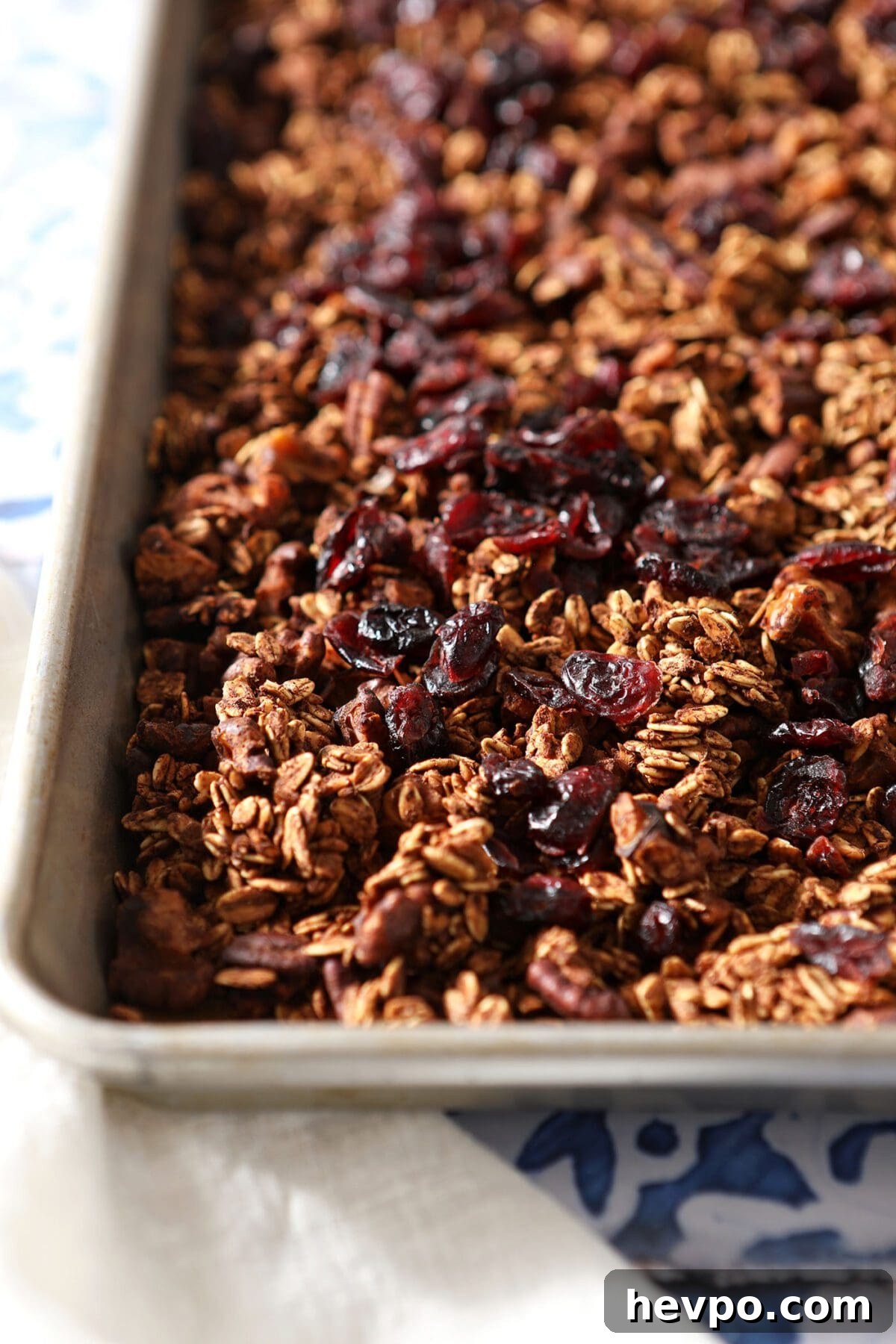 A baking sheet of granola with dried cranberries on a tiled surface
