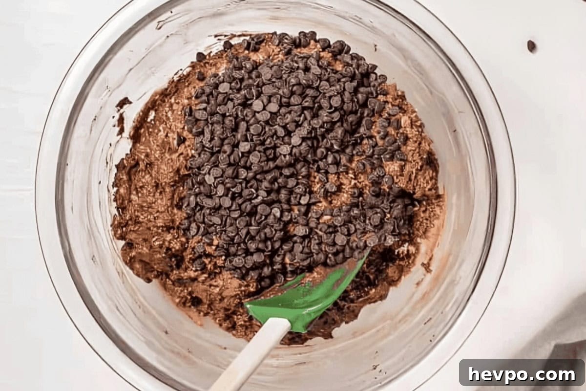 Decadent Chocolate Oatmeal Muffins with Chocolate Chips 7 stirring chocolate chips into chocolate oatmeal muffin batter with a rubber spatula.
