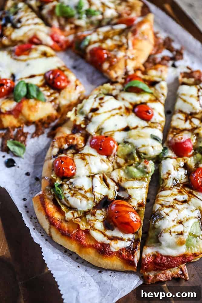 Top shot ravioli pizza on flatbread, topped with mozzarella cheese and cherry tomatoes.