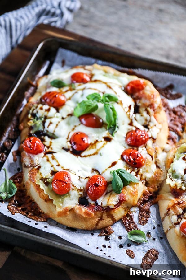 Top shot ravioli pizza on flatbread, topped with mozzarella cheese and cherry tomatoes.