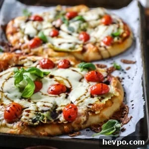 Top shot of small pizza made on naan and topped with mozzarella cheese and tomatoes.
