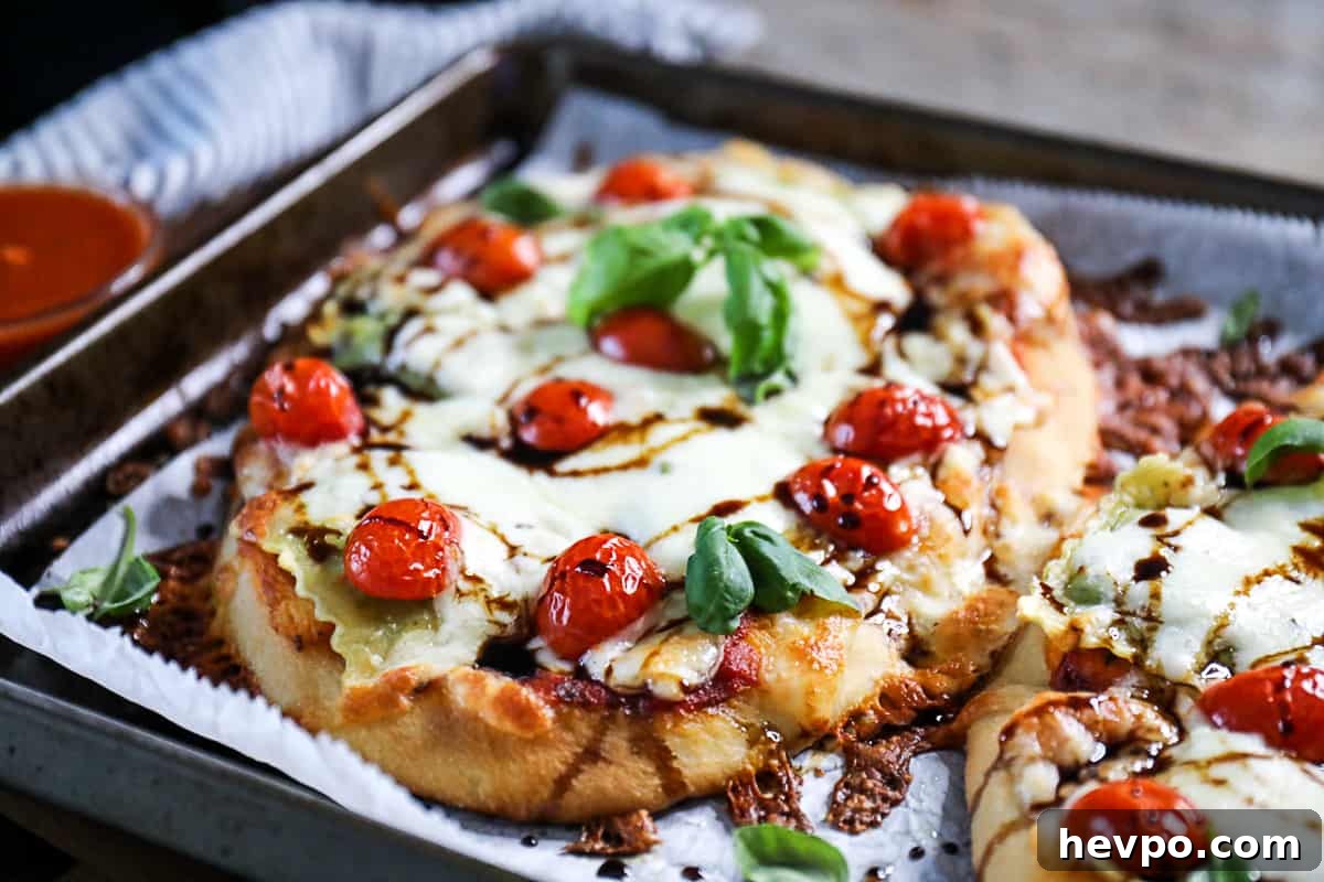 Top shot ravioli pizza on flatbread, topped with mozzarella cheese and cherry tomatoes.