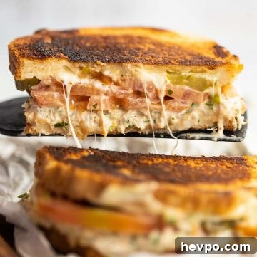 black spatula lifting half a tuna melt up with cheese pull