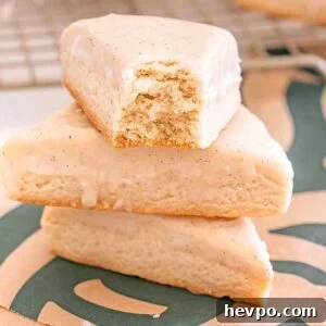 Three Starbucks Copycat Vanilla Bean Scones, one with a bite taken out, are stacked on a Starbucks napkin.