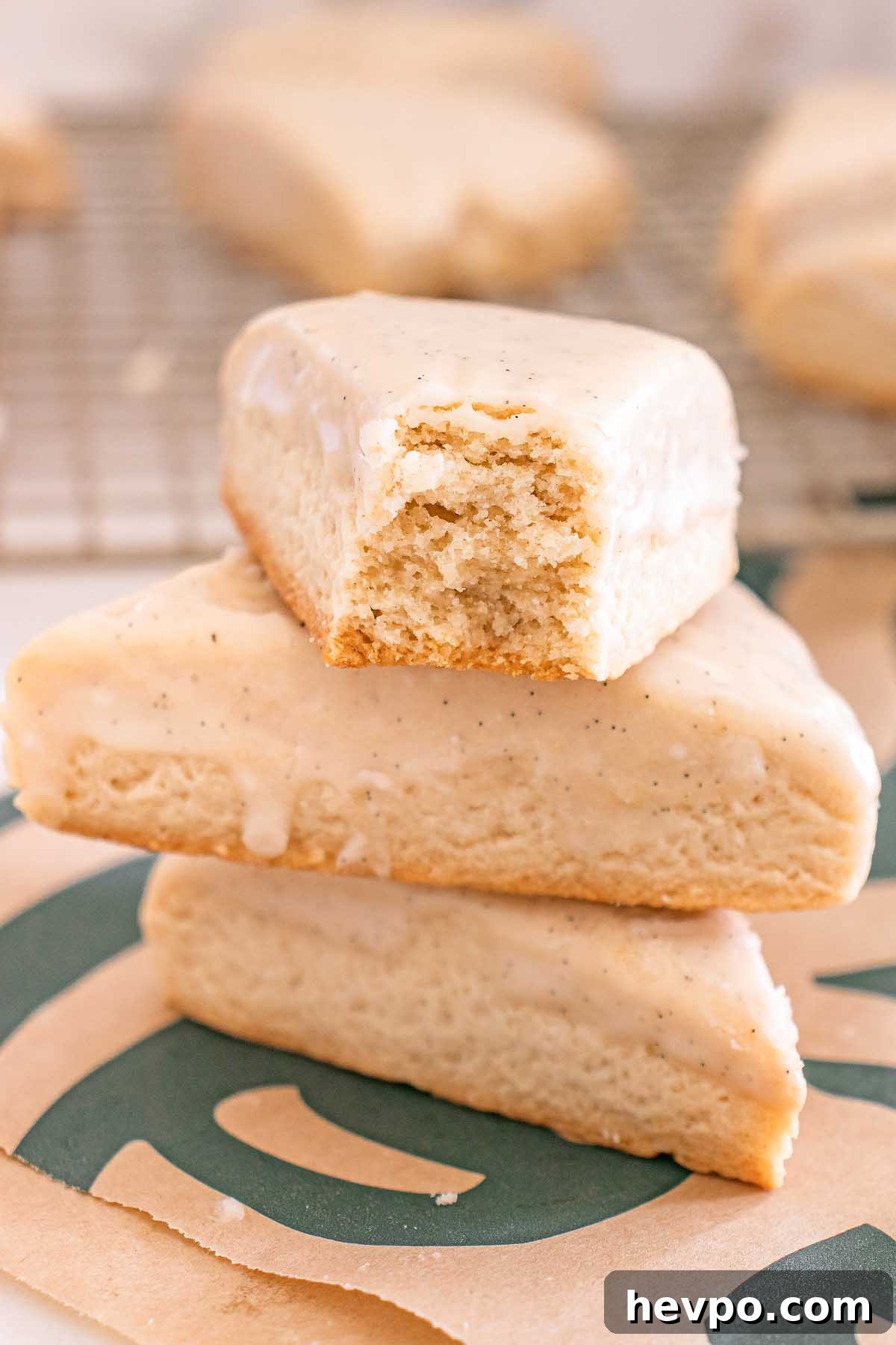 Three Starbucks Copycat Vanilla Bean Scones are stacked, with the top scone glazed and showing a bite taken out.