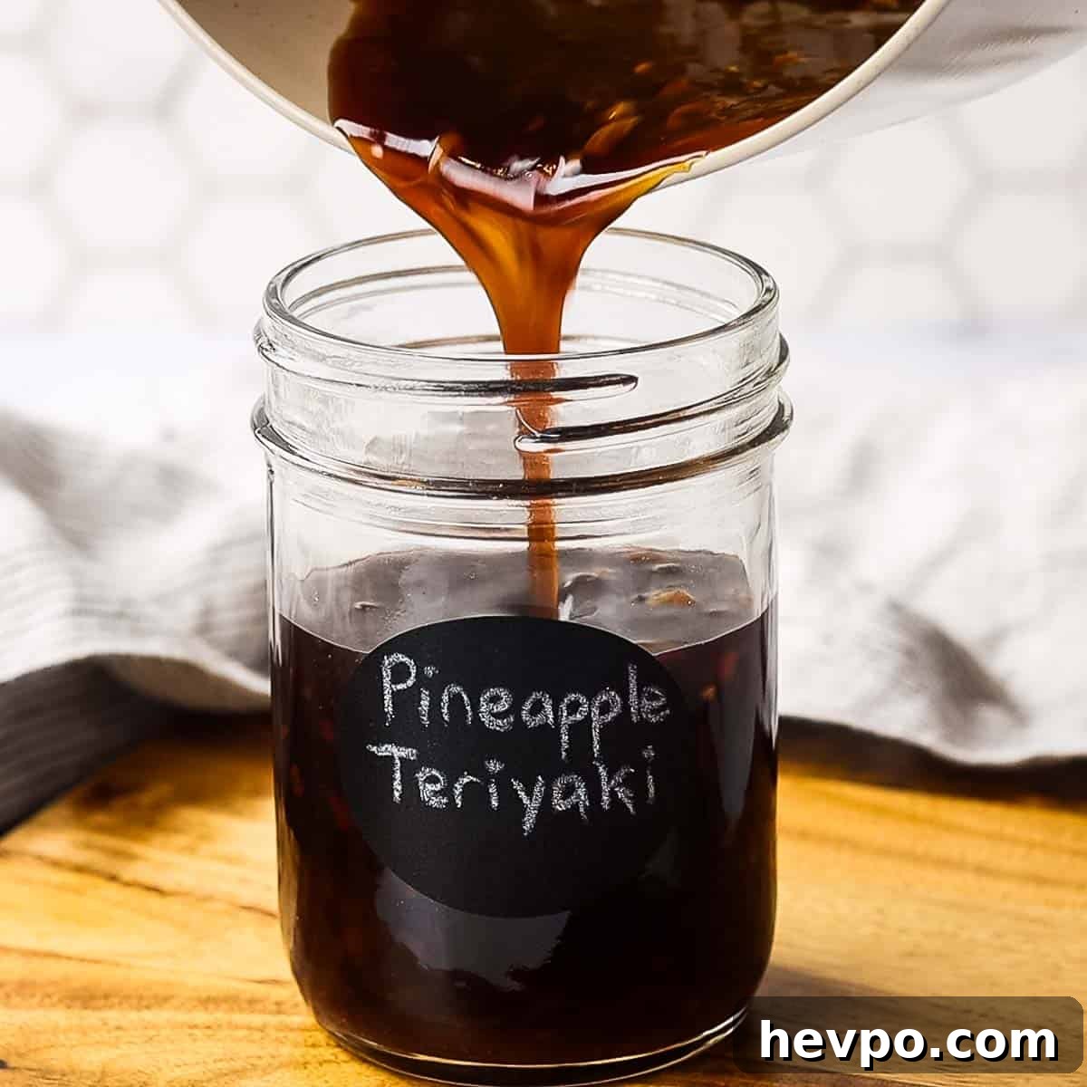 pouring pineapple teriyaki sauce in a jar labelled pineapple teriyaki