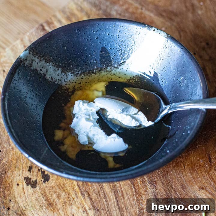 small black bowl on wooden board with cornflour, soy sauce and toasted sesame oil for a stir fry dressing