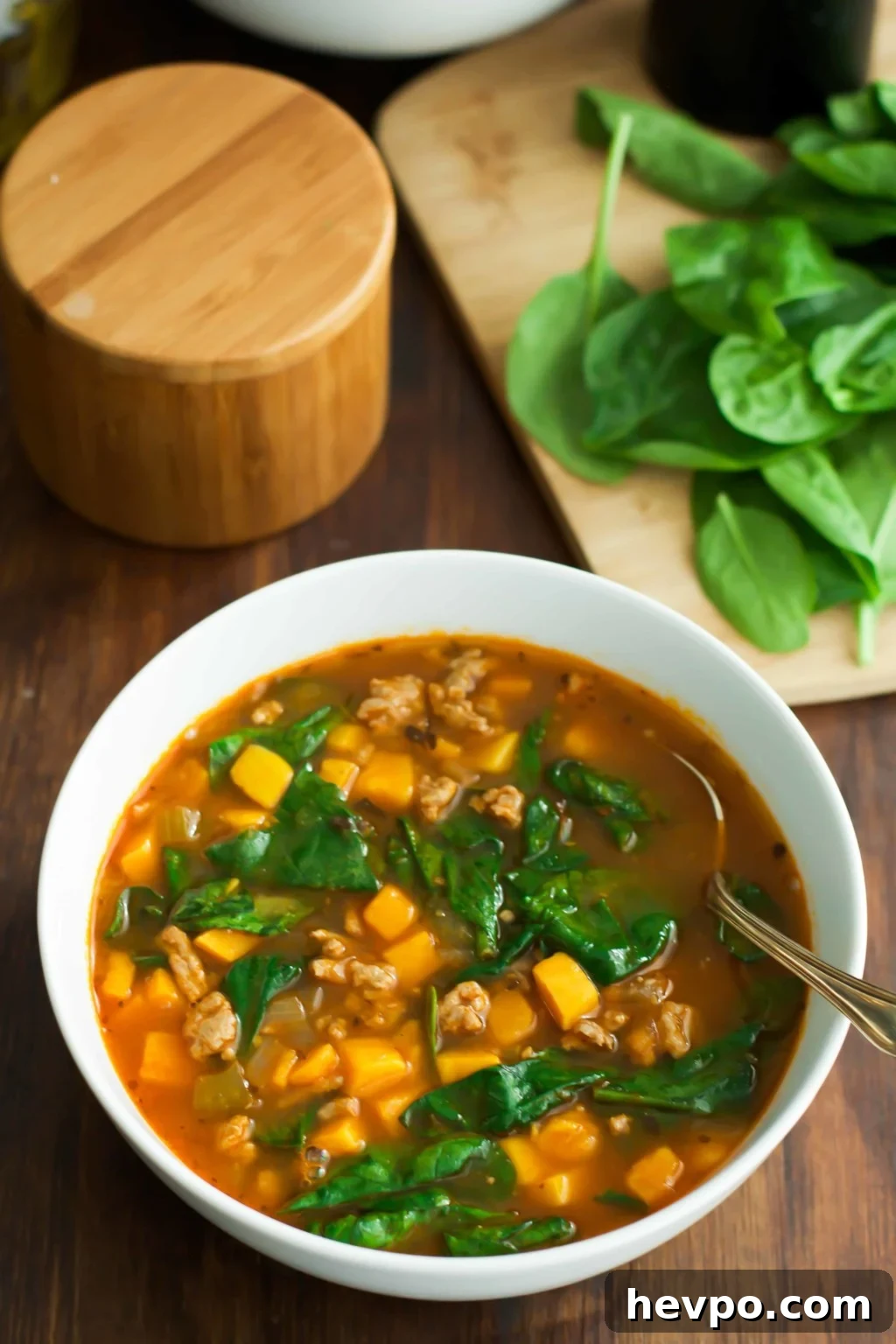 Spinach Sweet Potato Soup-2 A white bowl with spinach sweet potato soup with a spoon inside.