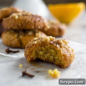 Melomakarona: Traditional Greek Christmas Honey Cookies Recipe 11 Greek Christmas honey cookie with a bite out of it on baking paper with more in the background.