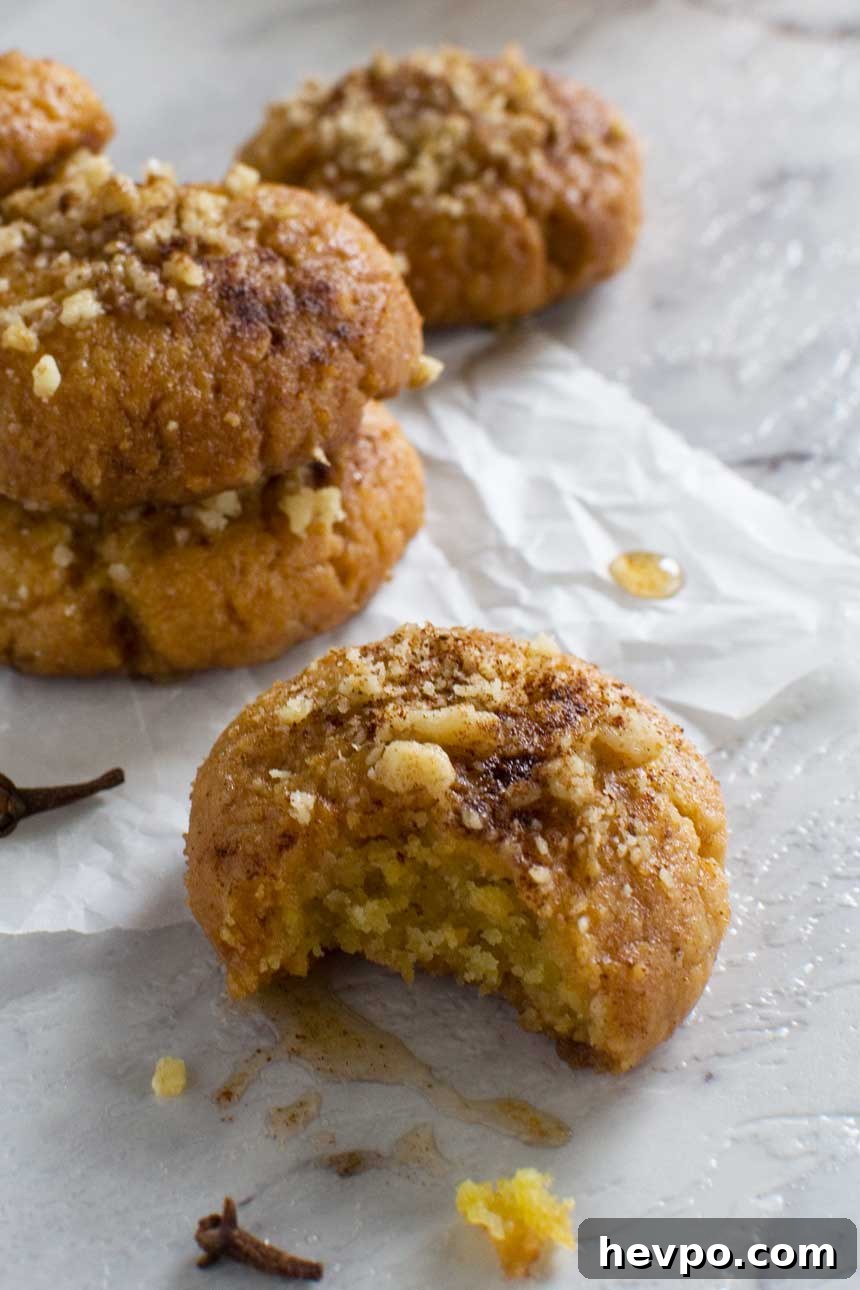 Melomakarona: Traditional Greek Christmas Honey Cookies Recipe 6 A closeup of a Greek Christmas honey cookie or melomakarona with a bite out of it and with more cookies in the background