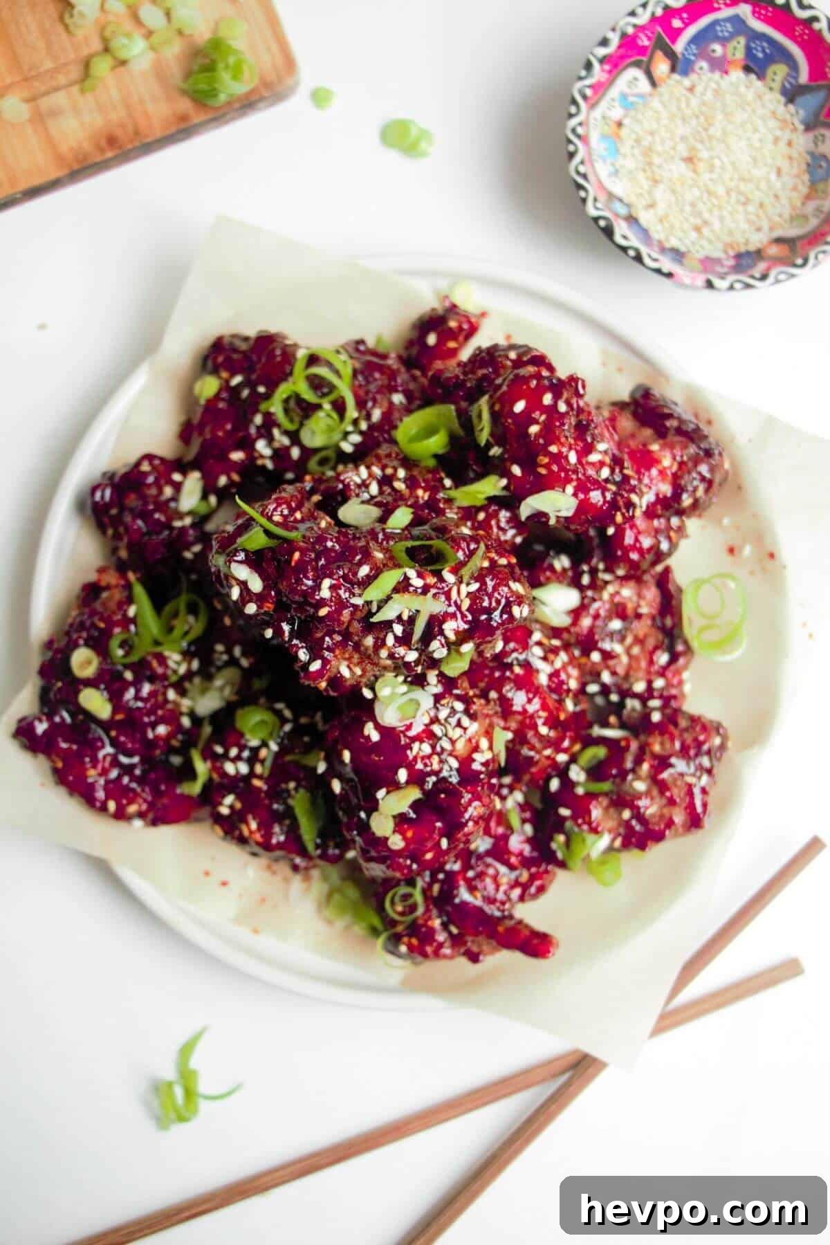 Crispy Korean Fried Chicken Recipe: Extra Crunch & Sticky Sauce 2 Pile of crispy Korean fried chicken on a small white plate with sesame seeds on the side.