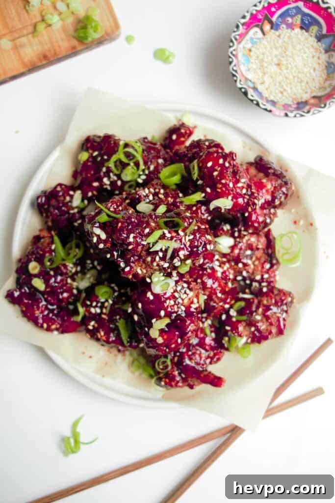 Crispy Korean Fried Chicken Recipe: Extra Crunch & Sticky Sauce 12 Pile of crispy Korean fried chicken on a small white plate with sesame seeds on the side.