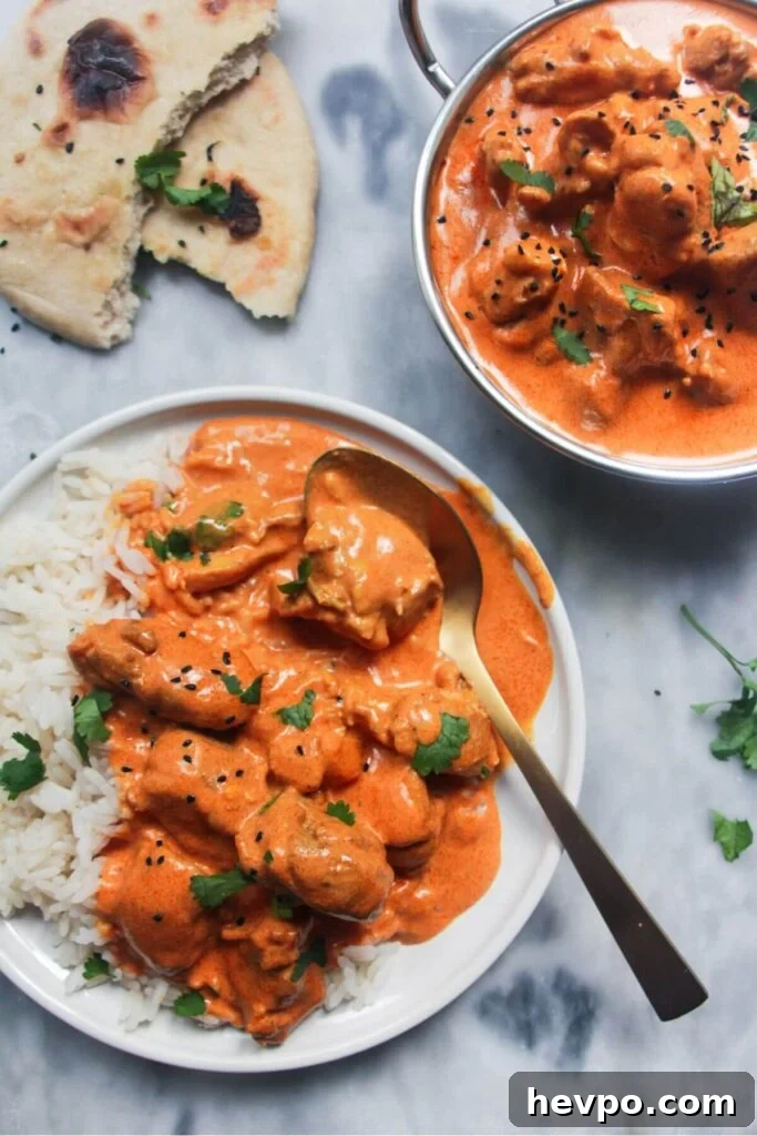 Crispy Korean Fried Chicken Recipe: Extra Crunch & Sticky Sauce 15 White plate with rice and butter chicken with bowl of butter chicken in the background and garlic naan.