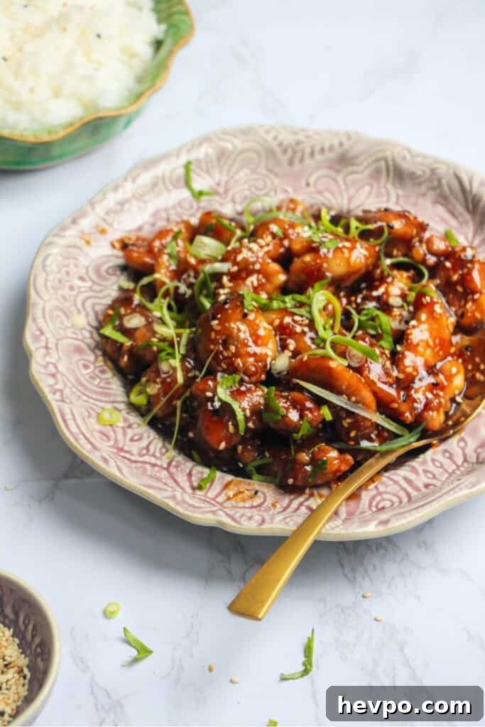 Crispy Korean Fried Chicken Recipe: Extra Crunch & Sticky Sauce 16 Honey sesame chicken topped with cilantro and scallions on a pink plate.