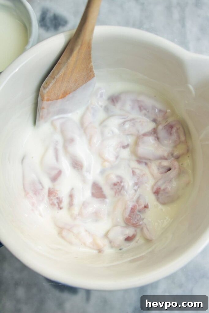 Crispy Korean Fried Chicken Recipe: Extra Crunch & Sticky Sauce 4 Chicken mixed with yogurt and spices in a large white bowl.