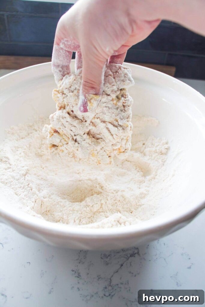Crispy Korean Fried Chicken Recipe: Extra Crunch & Sticky Sauce 6 Hand dredging chicken thigh in flour and spices.