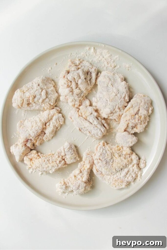 Crispy Korean Fried Chicken Recipe: Extra Crunch & Sticky Sauce 7 Pieces of dredged chicken on a large white plate.