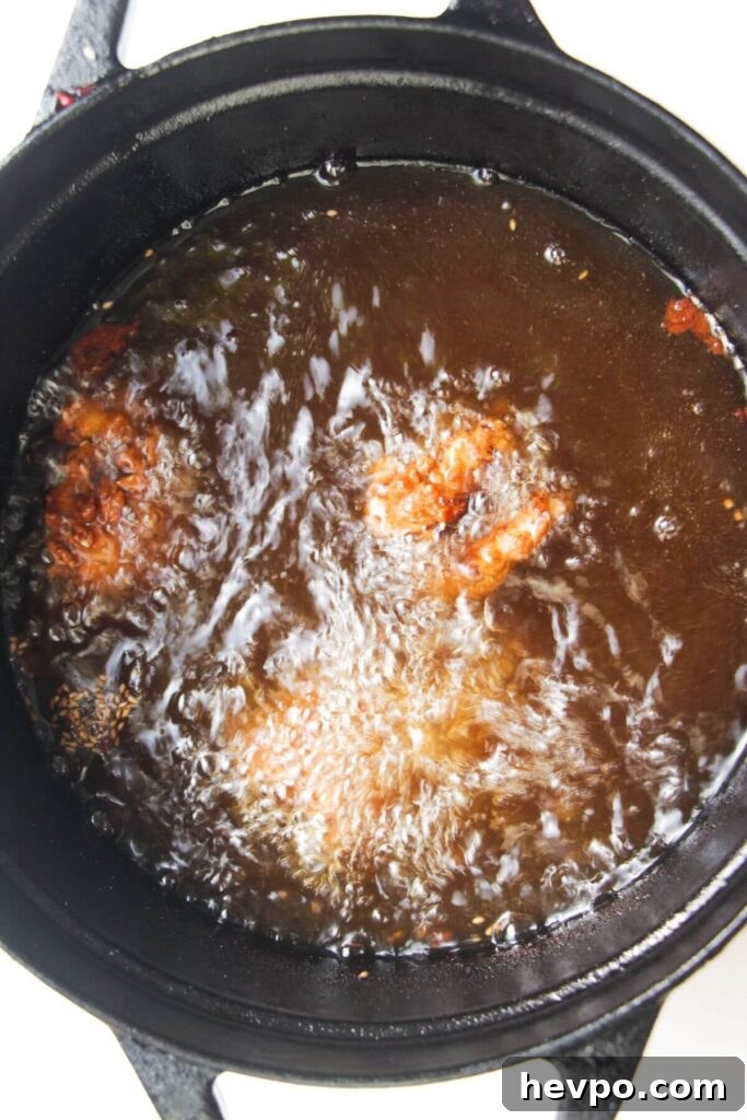Crispy Korean Fried Chicken Recipe: Extra Crunch & Sticky Sauce 8 Pieces of chicken frying in a pot of hot oil.