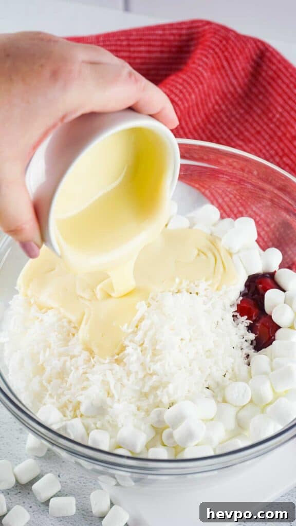 Light and Creamy Cherry Fluff Dessert Recipe 5 pouring condensed milk into cherry fluff ingredients in glass bowl